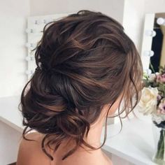 a woman with brown hair is looking at herself in the mirror and has her back to the camera