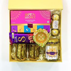 an open gift box filled with assorted chocolates and candies in gold foil