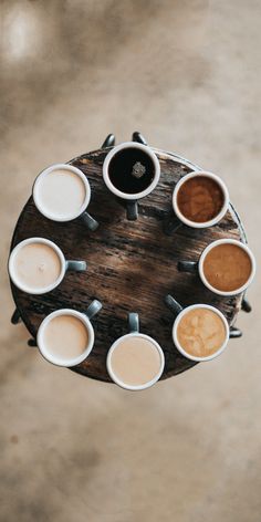 several cups of coffee are arranged on a table top with their lids down and one cup is in the middle