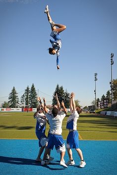 a group of young men standing on top of a tennis court holding hands in the air