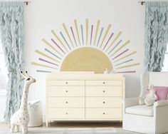 a baby's room with a dresser, chair and sun mural on the wall