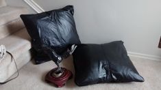 two black pillows sitting on the ground next to a stair case and a red object