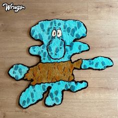 a blue stuffed animal holding a piece of wood in its paws on a wooden floor