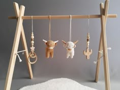 several wooden toys hanging from hooks on a white carpeted floor in front of a gray wall