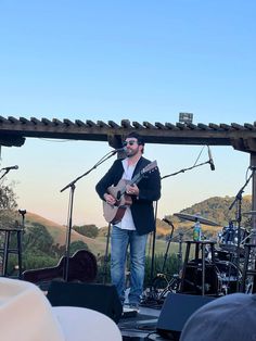 a man standing on top of a stage holding a guitar