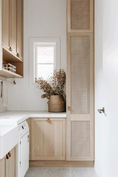 a kitchen with white counter tops and wooden cabinets in front of a window next to a washer and dryer