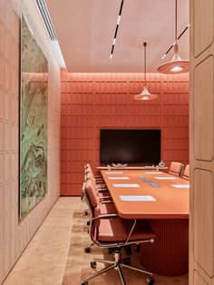 an orange conference table in the middle of a meeting room with chairs and a television mounted to the wall