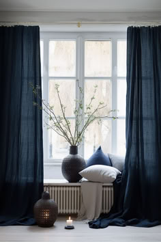 two vases with flowers in them sit on a window sill next to blue drapes