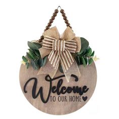 a wooden sign with a bow hanging from it's side that says welcome to our home