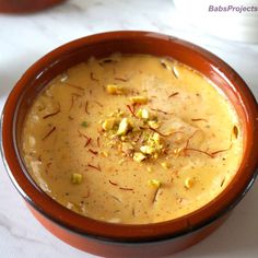 a brown bowl filled with soup on top of a white table next to spoons