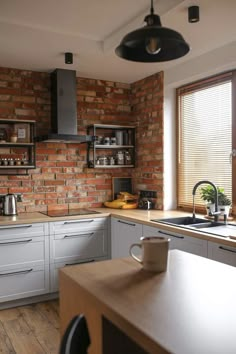 a kitchen with white cabinets and brick wall behind the countertop, along with a coffee maker