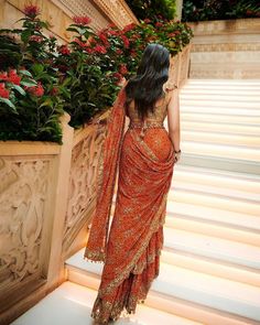 a woman in an orange sari walking up some steps