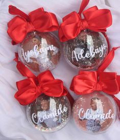 four personalized christmas ornaments with red bows