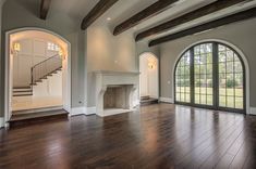 an empty living room with wood flooring and arched doorways leading to a staircase