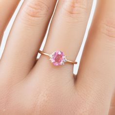 a woman's hand with a pink diamond ring on her left hand and the other hand holding an engagement ring