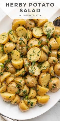 a white plate topped with potatoes and parsley on top of a marble countertop