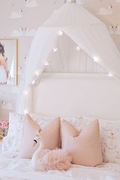 a white bed topped with lots of pillows next to a pink swan pillow on top of it