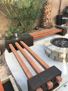 an outdoor fire pit surrounded by wooden benches and planters in the back yard area