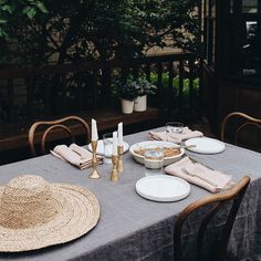 a table set with plates, silverware and straw hats for an outdoor dinner party