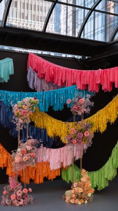 colorful streamers hanging from the ceiling in an indoor space with flowers and greenery