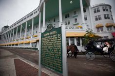 a horse drawn carriage parked in front of a large white and green building with yellow trim