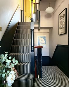 the stairs are lined with black and white striped carpet, along with potted plants