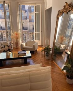 a living room filled with furniture and a large mirror on top of a wooden floor