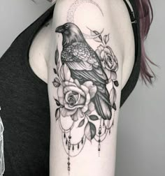 a woman's arm with a bird and roses tattoo on the left upper arm