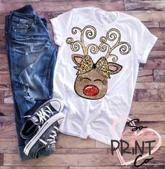 a t - shirt with a reindeer's head on it next to jeans and sneakers