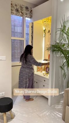 a woman standing in front of a bathroom mirror next to a plant and window sill