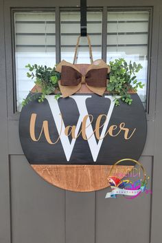 a wooden sign with a bow hanging from it's side on the front door