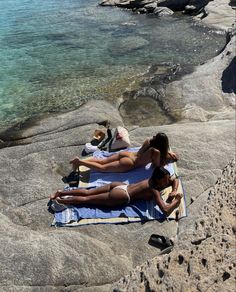 two people laying on towels near the water