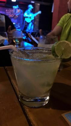 a close up of a drink on a table at a bar with people in the background