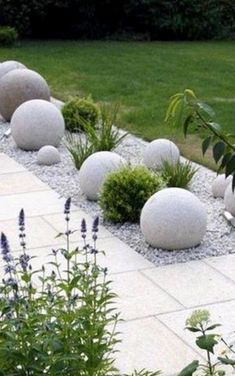 some white rocks and plants in the middle of a yard with grass on either side