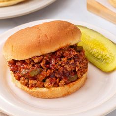 a sloppy joe sandwich on a plate with a pickle