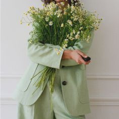 a woman in a green suit holding flowers