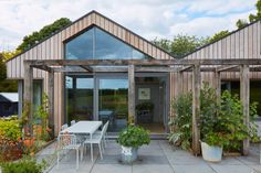 an outdoor patio with tables and chairs next to plants on the side of the house