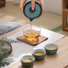 someone pouring tea into small cups on a table