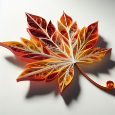 a colorful paper leaf is shown on a white surface