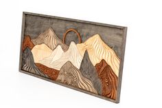 a wooden wall hanging with mountains in the middle and a basket on it's side