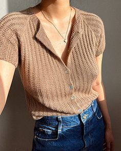 a woman wearing a brown sweater and blue jeans is posing for the camera with her hand on her hip