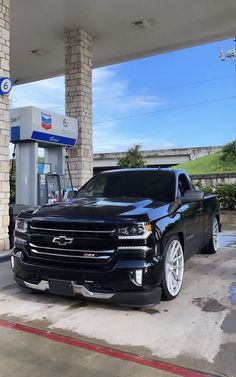 a black truck parked in front of a gas station