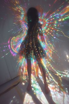 a woman standing in the middle of a room with colorful lights on her body and wings