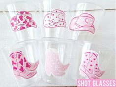 six shot glasses with pink cowboy hats and stars on the side, set in clear plastic cups