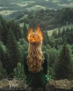 a woman sitting on top of a rock with a fireball in her hair looking out over a forest