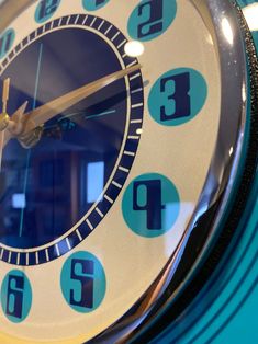 a close up of a clock with blue numbers on it's face and hands