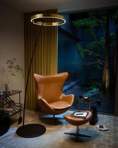 a modern living room with an orange leather chair and black round coffee table in front of the window