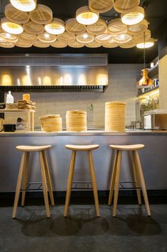 two stools sitting in front of a counter with cakes on it and lights hanging from the ceiling