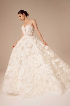 a woman in a white wedding dress with large leaves on the skirt and headband