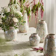 there are many vases that have flowers in them on the tablecloth and one is empty